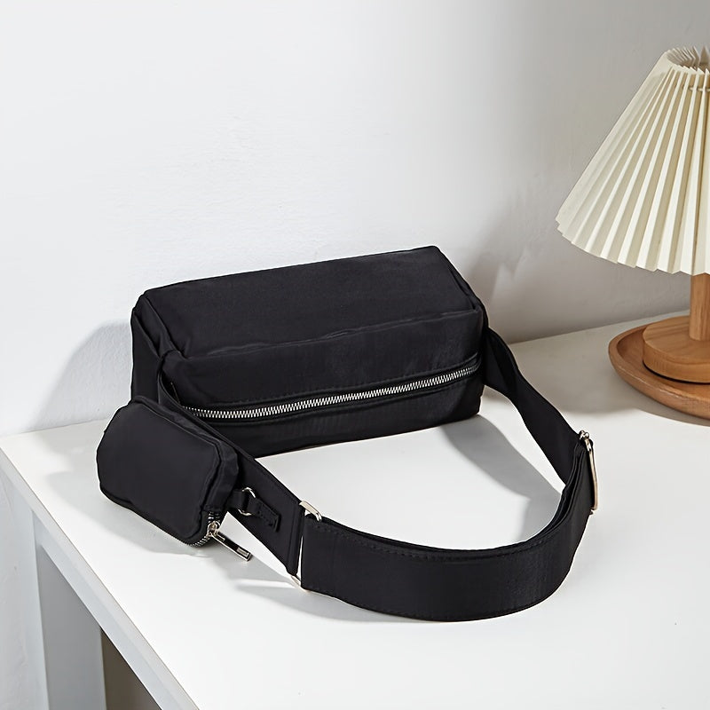 Marsupio nero elegante su tavolo bianco, con cerniera argentata e tasca aggiuntiva. Accessorio moda unisex, ideale per viaggi e uso quotidiano.