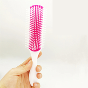 Spazzola per capelli bianca e rosa con setole in plastica, design ergonomico, ideale per districare e lisciare, accessorio essenziale per la cura dei capelli.