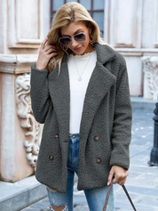 Donna con cappotto in pile grigio scuro, occhiali da sole, jeans strappati, maglia bianca; moda autunnale casual elegante.