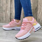 Scarpe da ginnastica rosa da donna con suola spessa bianca, dettagli dorati, indossate con jeans aderenti. Sneakers moda casual comode.