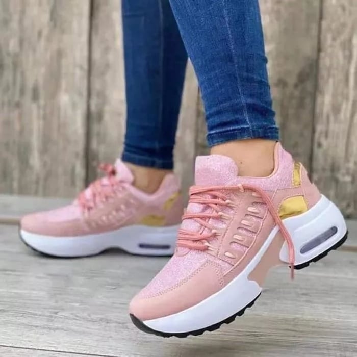 Scarpe da ginnastica rosa da donna con suola spessa bianca, dettagli dorati, indossate con jeans aderenti. Sneakers moda casual comode.