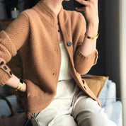 Donna con cardigan marrone in maglia, top bianco e pantaloni beige. Moda autunnale elegante, abbigliamento casual chic, stile contemporaneo.