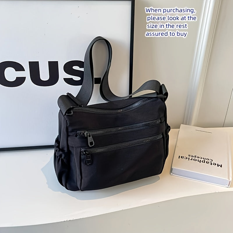 Borsa a tracolla nera con tasche multiple, design moderno, su tavolo bianco. Ideale per moda urbana e praticità quotidiana.