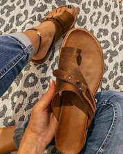 Sandali marroni in pelle con fibbia, indossati su tappeto leopardato. Moda estiva, calzature casual, stile boho chic.