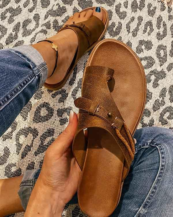 Sandali marroni in pelle con fibbia, indossati su tappeto leopardato. Moda estiva, calzature casual, stile boho chic.