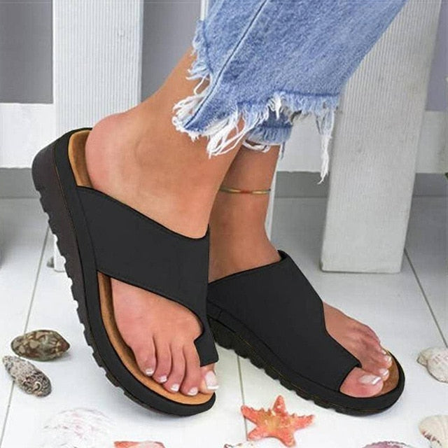 Sandali neri da donna con suola spessa, indossati con jeans strappati. Design casual estivo, perfetti per passeggiate sulla spiaggia.