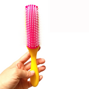 Spazzola per capelli con manico giallo e setole rosa, tenuta in mano. Accessorio per styling, ideale per districare e lisciare i capelli.