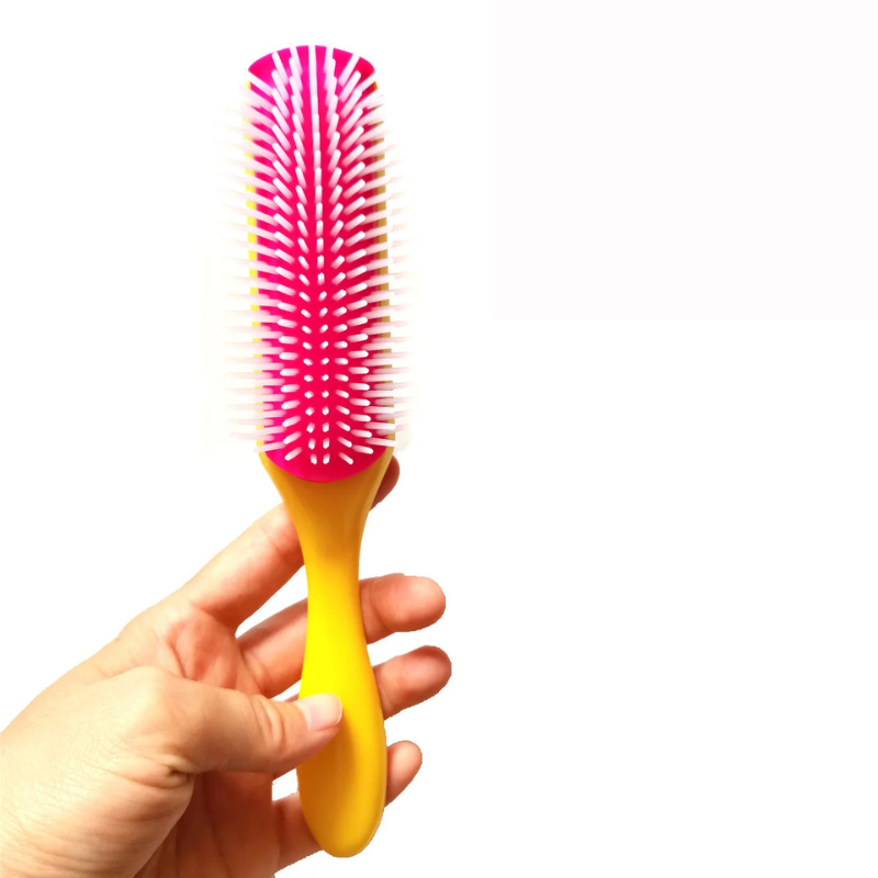 Spazzola per capelli con manico giallo e setole rosa, tenuta in mano. Accessorio per styling, ideale per districare e lisciare i capelli.