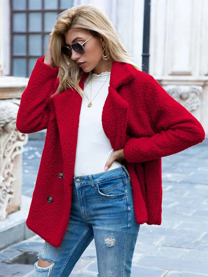 Giacca rossa in pelliccia sintetica, donna con occhiali da sole, jeans strappati, maglia bianca, moda autunnale, stile urbano elegante.