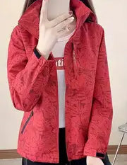 Giacca rossa donna con motivo floreale, zip frontale, indossata sopra maglietta bianca. Moda autunnale, abbigliamento casual elegante.