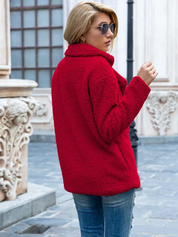 Donna con cappotto rosso in pelliccia sintetica, occhiali da sole, jeans blu, in strada urbana. Moda autunno inverno, stile casual elegante.