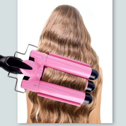 Ferro arricciacapelli triplo rosa su capelli ondulati biondi, styling professionale, acconciatura volumizzante, strumento per onde morbide.