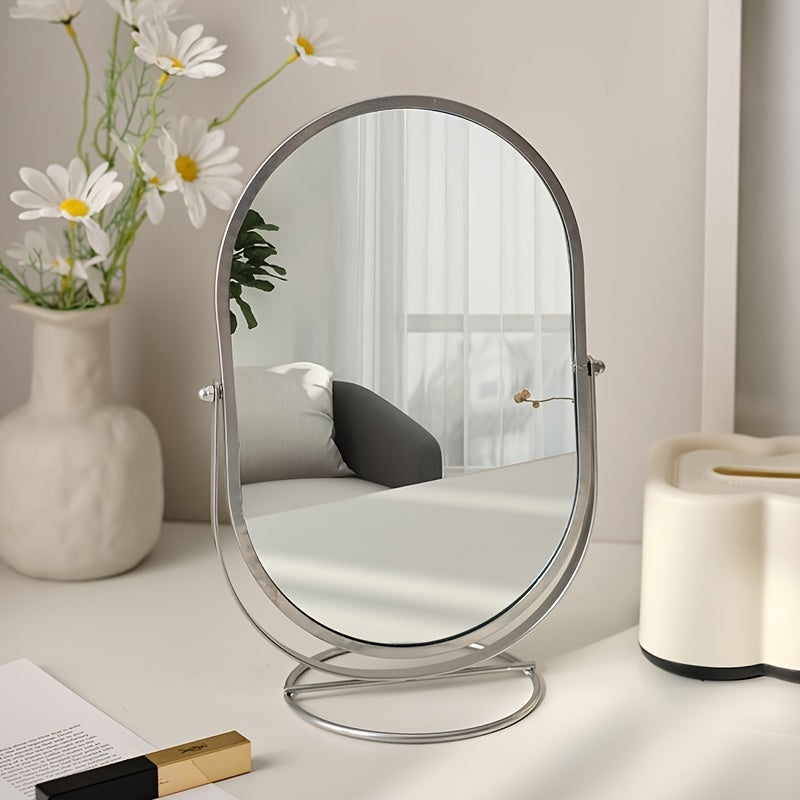 Specchio da tavolo ovale con cornice in metallo su scrivania bianca, accanto a vaso di fiori e rossetto. Design moderno per arredamento casa.