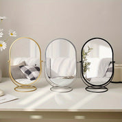 Specchio da tavolo ovale con cornice in metallo, disponibile in oro, argento e nero. Design moderno, ideale per arredamento camera da letto o bagno.