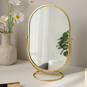 Specchio da tavolo ovale con cornice dorata, riflesso di piante e interni moderni, decorazione elegante per casa, design minimalista.
