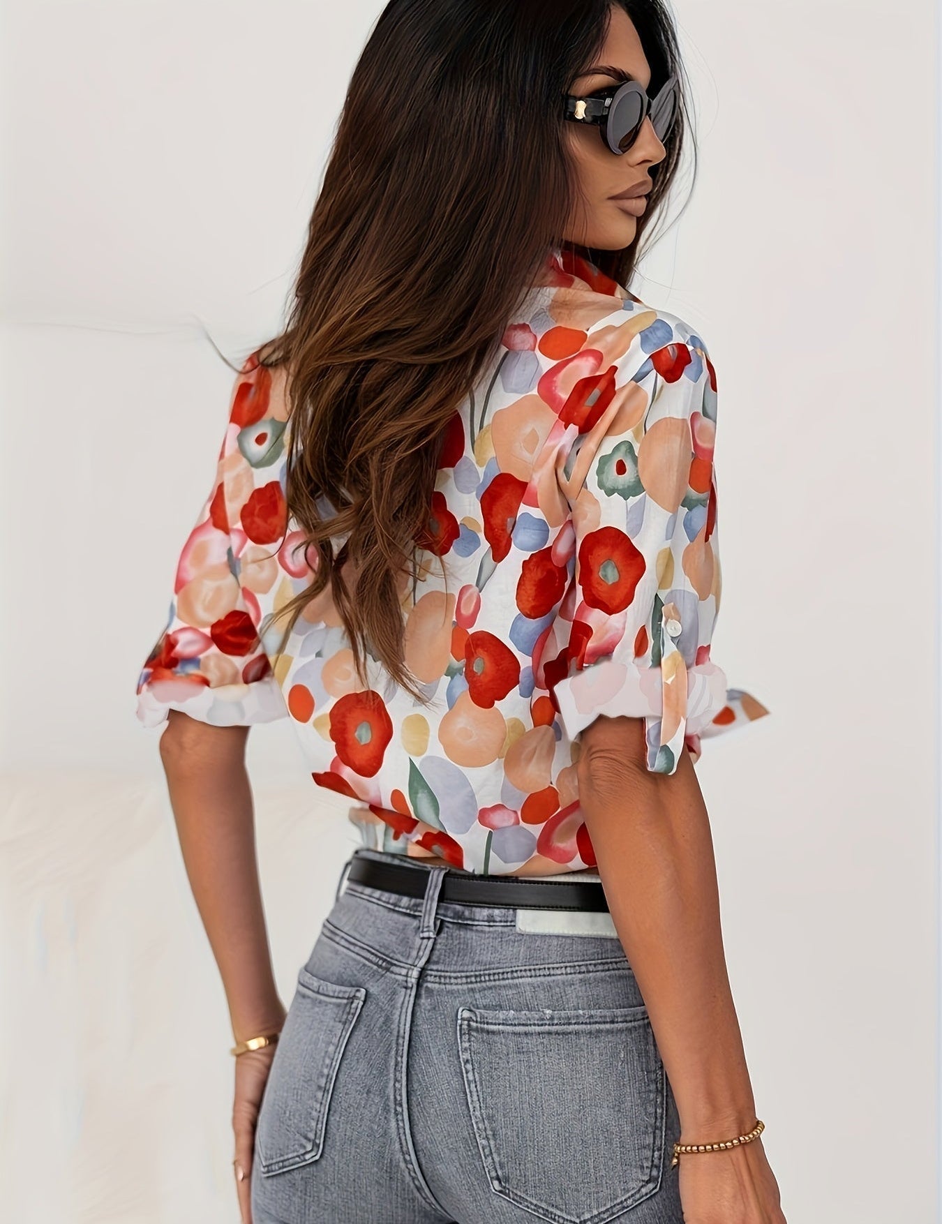 Donna con camicia a fiori colorati, jeans aderenti e occhiali da sole. Moda femminile, abbigliamento casual elegante, stile estivo.