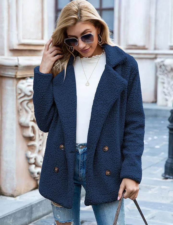 Donna con cappotto blu in lana bouclé, occhiali da sole, maglia bianca e jeans strappati. Moda autunnale, stile casual chic, abbigliamento femminile.