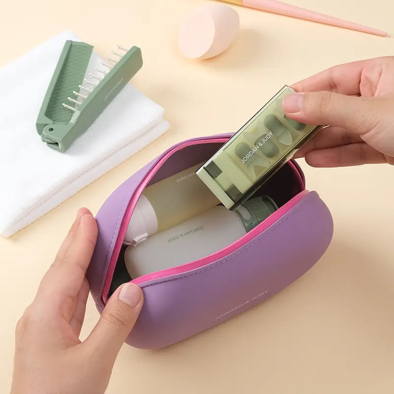 Astuccio da viaggio viola con cerniera rosa, contenente flaconi per cosmetici e accessori per la cura personale. Ideale per organizzare prodotti beauty.