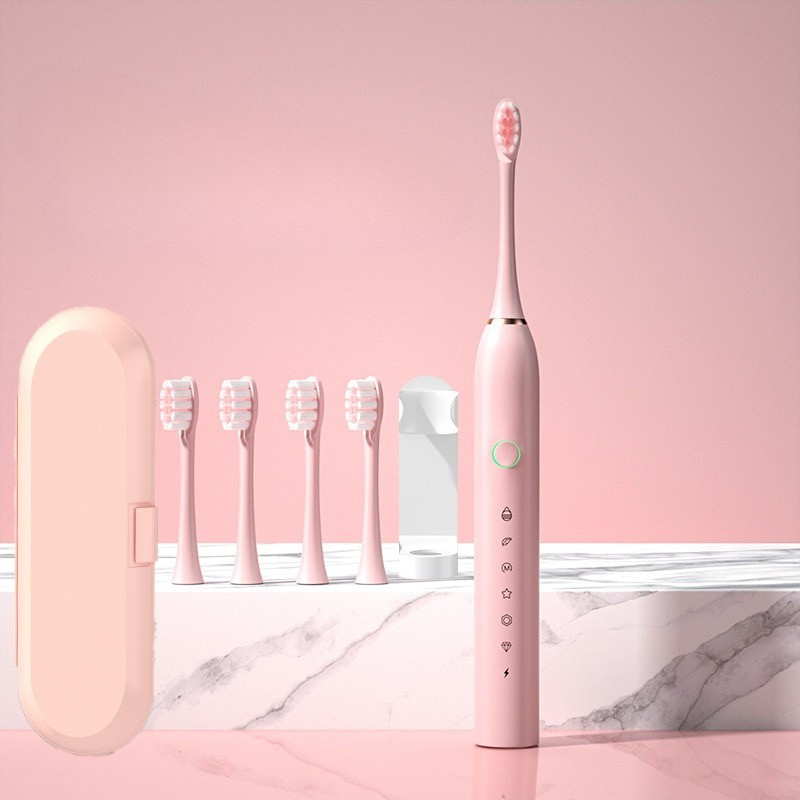 Spazzolino elettrico rosa con cinque testine di ricambio, custodia da viaggio e caricatore. Design elegante, ideale per igiene orale quotidiana.