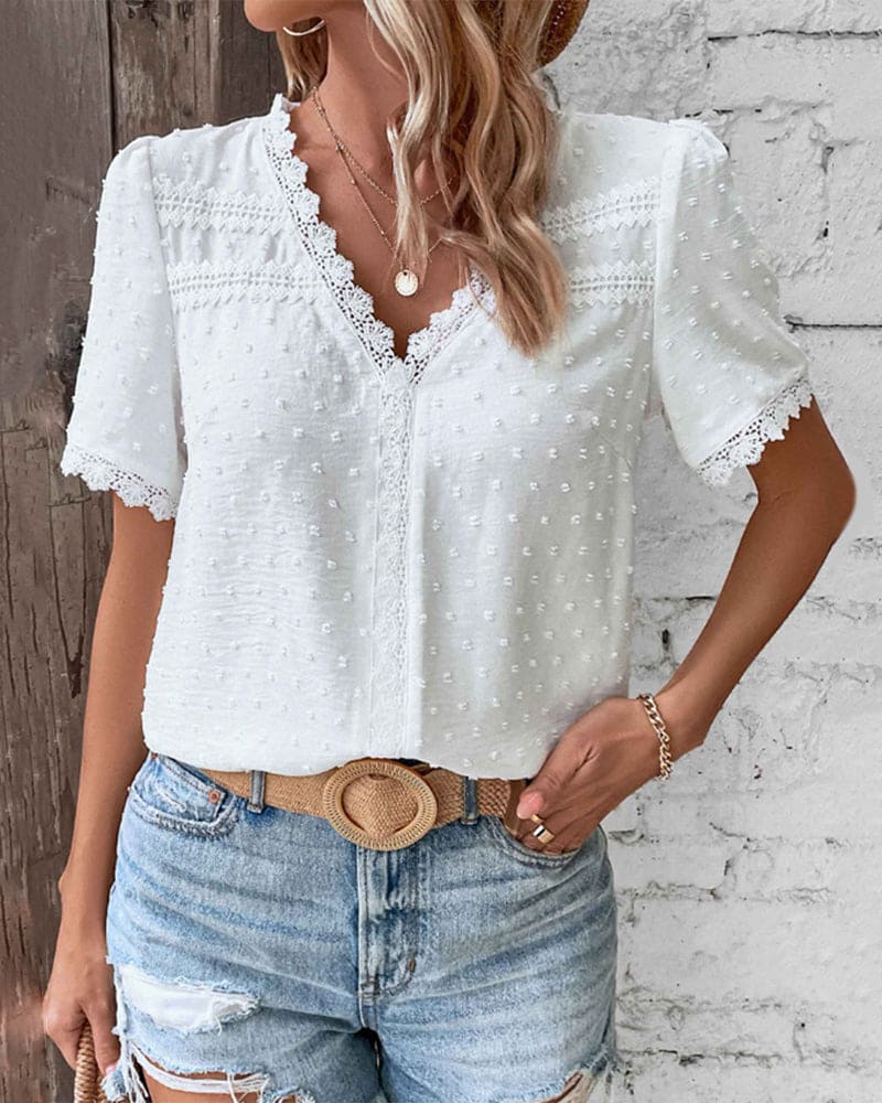 Donna con camicetta bianca in pizzo e jeans strappati, stile casual estivo. Accessori: cintura beige, collana e anello. Moda femminile trendy.