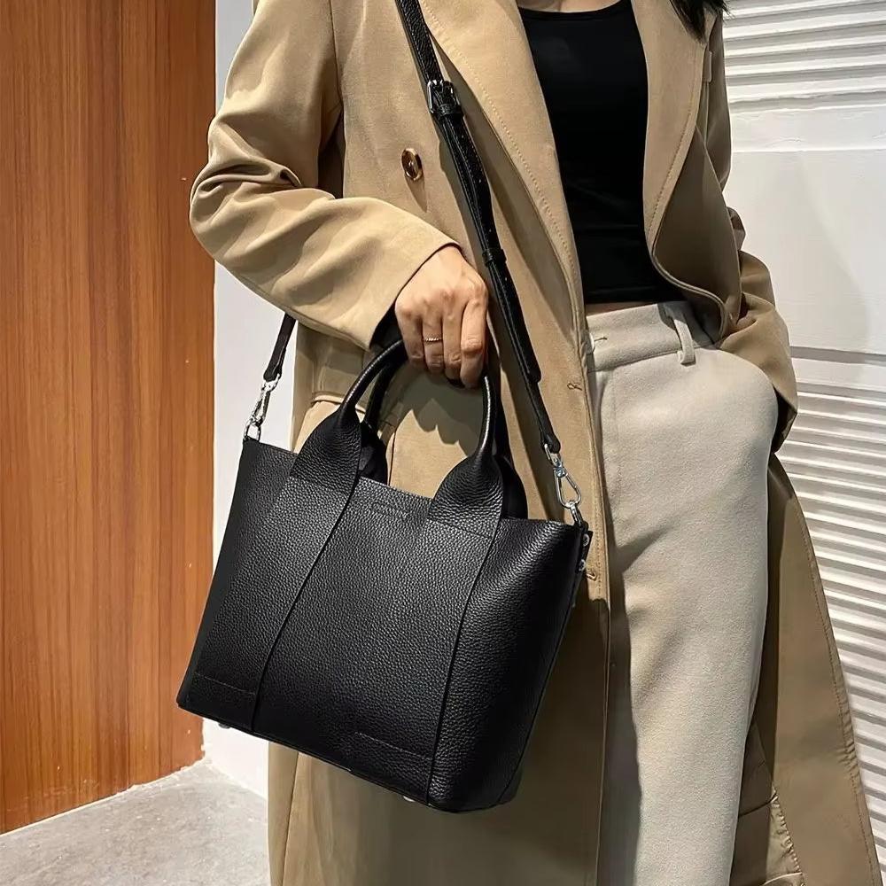 Donna con cappotto beige e borsa a tracolla nera in pelle, elegante e moderna. Accessorio moda femminile, perfetto per l'autunno.