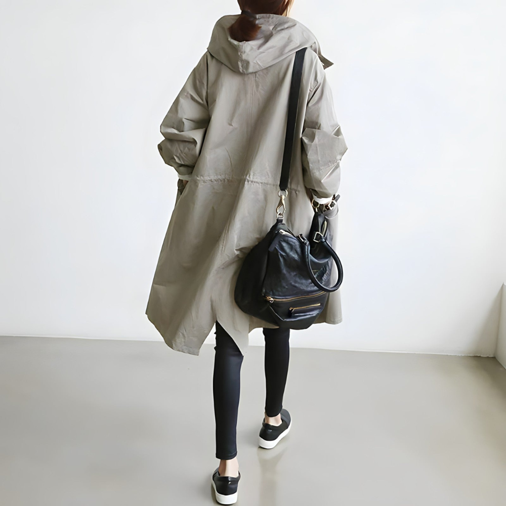 Donna con cappotto beige oversize, leggings neri e borsa a tracolla in pelle nera. Moda casual autunnale, abbigliamento urbano elegante.