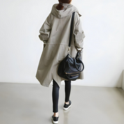 Donna con cappotto beige oversize, leggings neri e borsa a tracolla in pelle nera. Moda casual autunnale, abbigliamento urbano elegante.