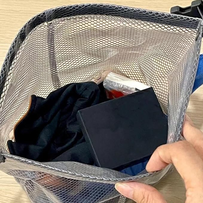 Borsa organizer in rete grigia con oggetti personali, tra cui un libro nero e vestiti. Ideale per viaggi, organizzazione bagagli, accessori viaggio.