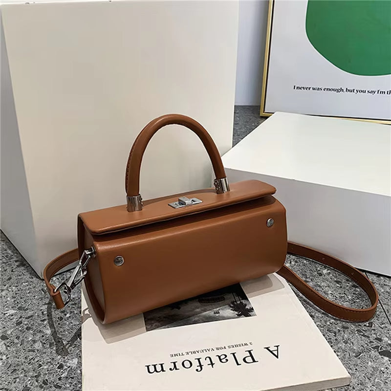 Borsa a mano in pelle marrone su sfondo minimalista, con tracolla regolabile e chiusura metallica. Accessorio moda elegante e versatile.