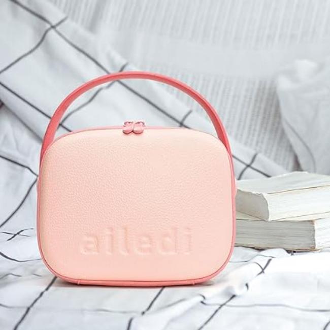 Borsa cosmetica rosa con manico, design compatto, su sfondo a righe bianche e nere. Ideale per viaggi, organizzazione trucco, accessori donna.