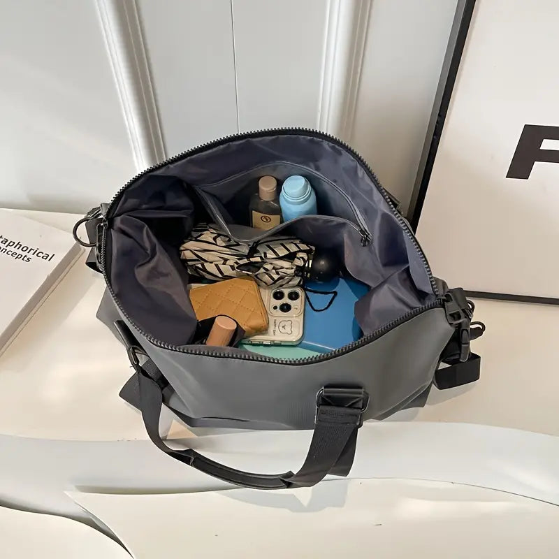 Borsa a tracolla grigia aperta con oggetti personali: smartphone, portafoglio, cosmetici. Design moderno, ideale per moda e praticità quotidiana.