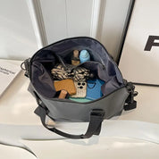 Borsa a tracolla grigia aperta con oggetti personali: smartphone, portafoglio, cosmetici. Design moderno, ideale per moda e praticità quotidiana.
