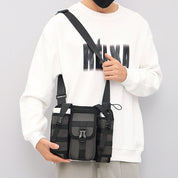 Borsa a tracolla nera unisex, design moderno con tasche multiple, indossata da persona in felpa bianca. Accessorio moda casual e pratico.