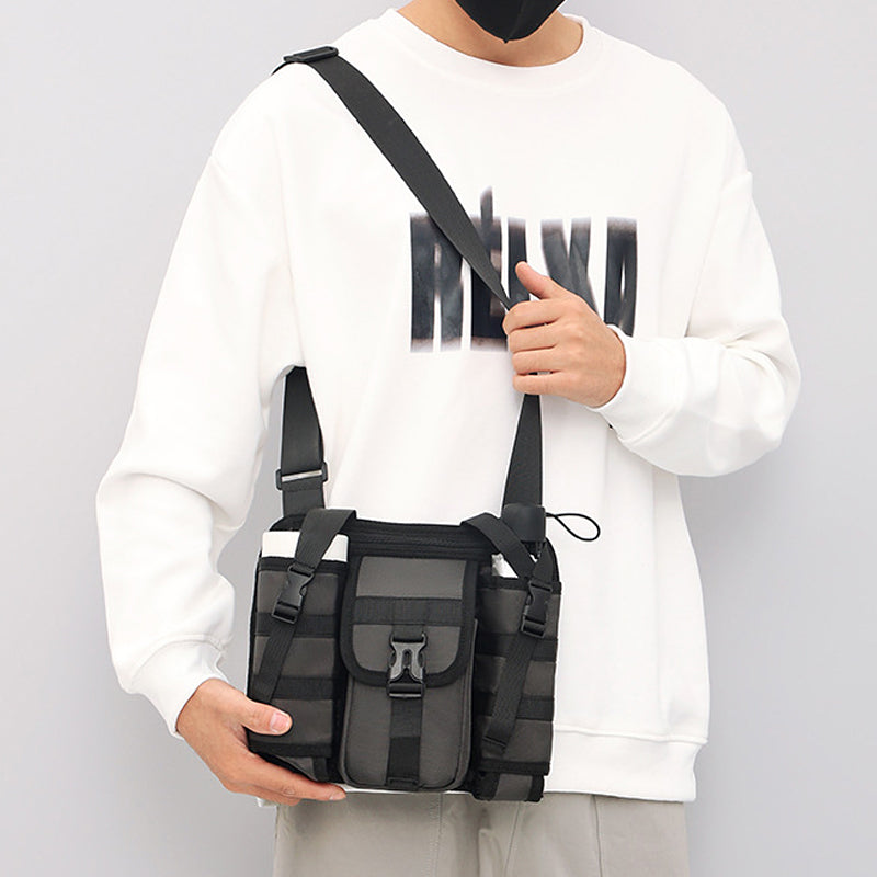 Borsa a tracolla nera unisex, design moderno con tasche multiple, indossata da persona in felpa bianca. Accessorio moda casual e pratico.