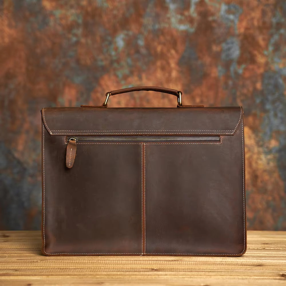 Elegante valigetta in pelle marrone su sfondo sfocato, ideale per lavoro e ufficio. Design classico con manico robusto e cuciture a vista.