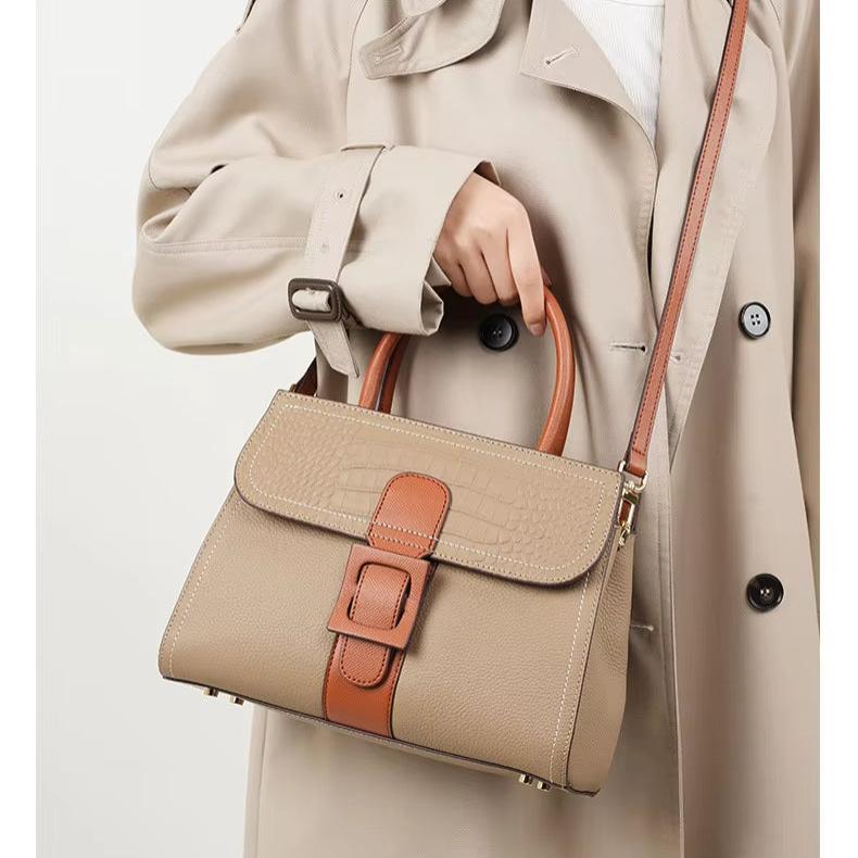 Borsa a mano beige in pelle con dettagli marroni, fibbia decorativa, tracolla regolabile. Elegante accessorio moda donna, stile classico.