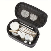 Borsa da toilette nera aperta con scomparti, contenente flaconi da viaggio, dischetti di cotone, asciugamano e accessori per la cura personale.
