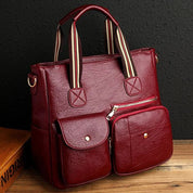 Borsa a mano in pelle rossa con tasche frontali, manici a righe, design elegante. Accessorio moda donna, ideale per lavoro e tempo libero.
