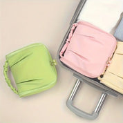 Valigia aperta con organizer da viaggio verde e rosa, ideali per ottimizzare lo spazio. Accessori perfetti per bagagli ordinati e organizzati.