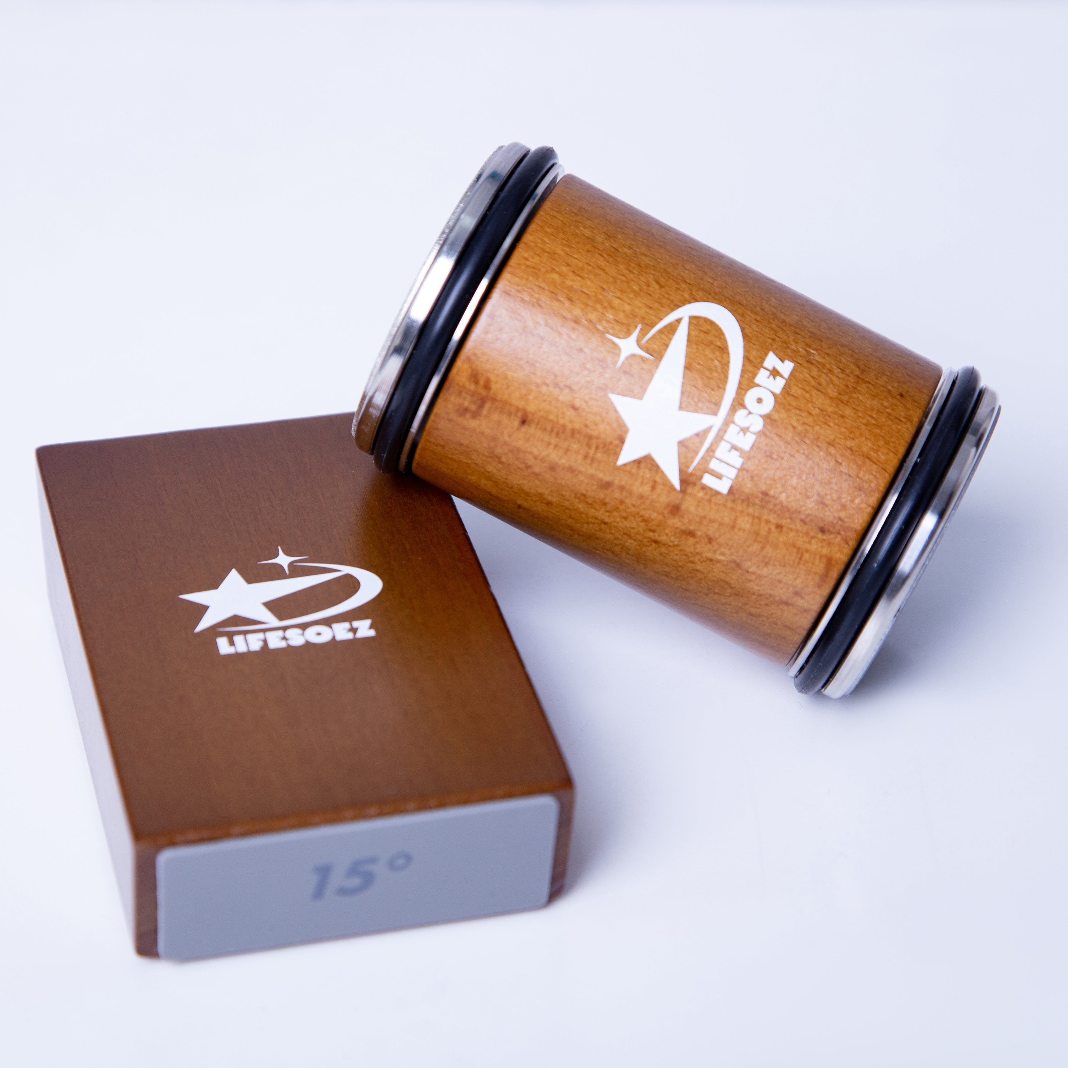 Contenitore cilindrico in legno con logo bianco "LIFESOEZ", accanto a scatola marrone con etichetta "15°". Design elegante e moderno.