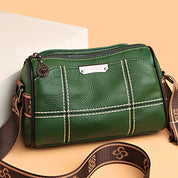 Borsa a tracolla verde in pelle con cuciture bianche, cerniera superiore e tracolla regolabile marrone. Elegante accessorio moda donna.