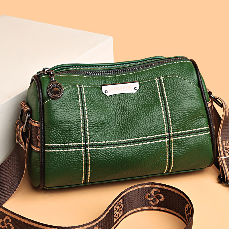 Borsa a tracolla verde in pelle con cuciture bianche, cerniera superiore e tracolla regolabile marrone. Elegante accessorio moda donna.