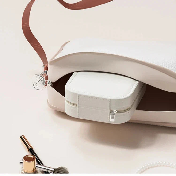 Borsa bianca in pelle aperta con pochette interna, accessori trucco e perle. Elegante e versatile, ideale per moda femminile e accessori di lusso.