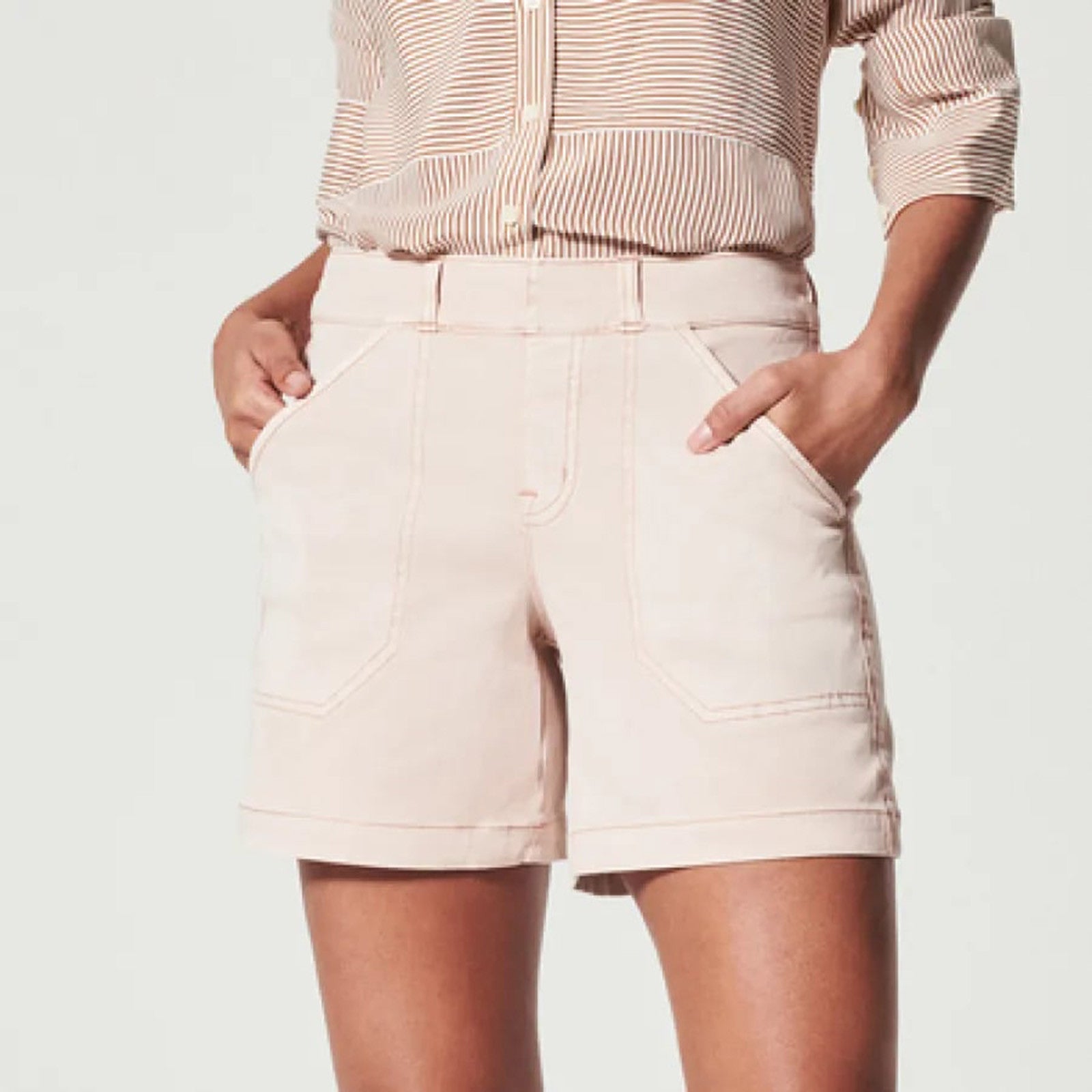 Donna con camicia a righe e shorts beige, tasche frontali, stile casual. Abbigliamento estivo femminile, moda contemporanea.