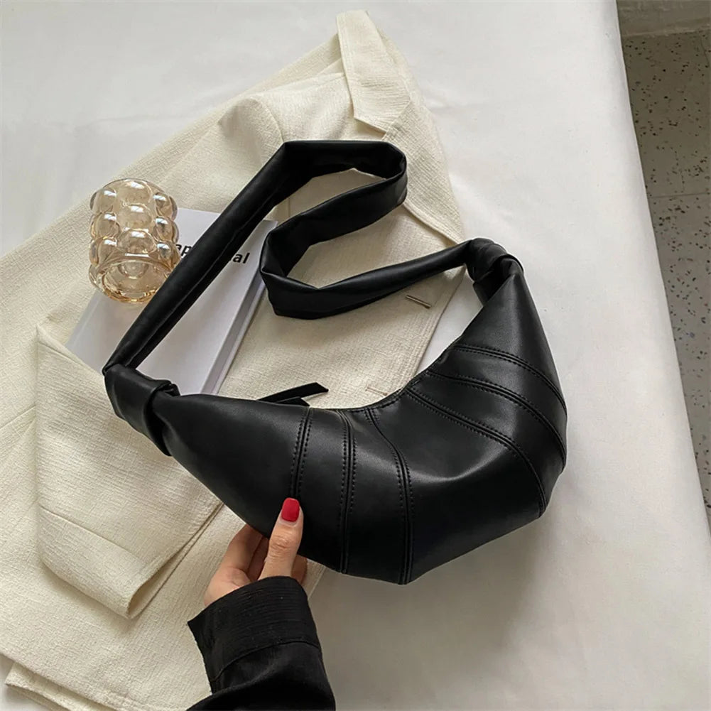 Borsa a tracolla nera in pelle su giacca beige, design moderno, accessorio moda donna, stile elegante, perfetta per look casual e formali.