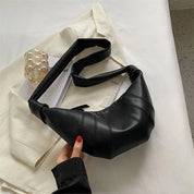 Borsa a tracolla nera in pelle su giacca beige, design moderno, accessorio moda donna, stile elegante, perfetta per look casual e formali.
