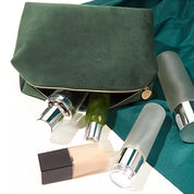 Borsa cosmetica verde con cerniera, contenente flaconi di prodotti skincare. Elegante e pratica per organizzare cosmetici e accessori di bellezza.
