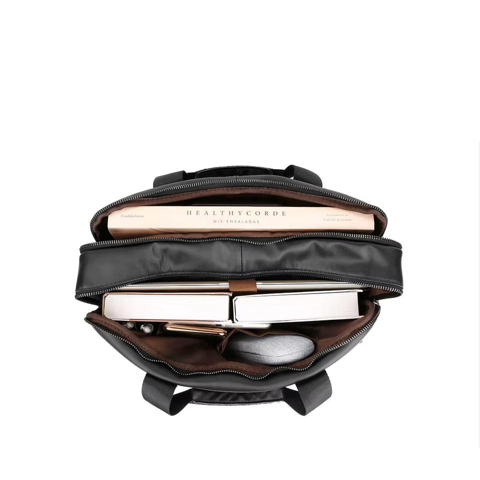 Zaino nero aperto con libri, quaderno, astuccio e occhiali all'interno. Design elegante, ideale per scuola o lavoro. Tasche multiple, capiente.