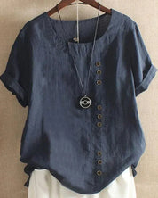 Maglietta donna in lino blu scuro con bottoni decorativi asimmetrici, maniche corte e collana pendente, appesa su gruccia.