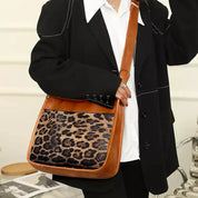 Borsa a tracolla in pelle marrone con stampa leopardata, indossata da una persona in abito nero. Accessorio moda elegante e trendy.